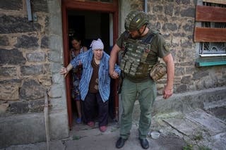A police officer evacuates an elderly woman from her house